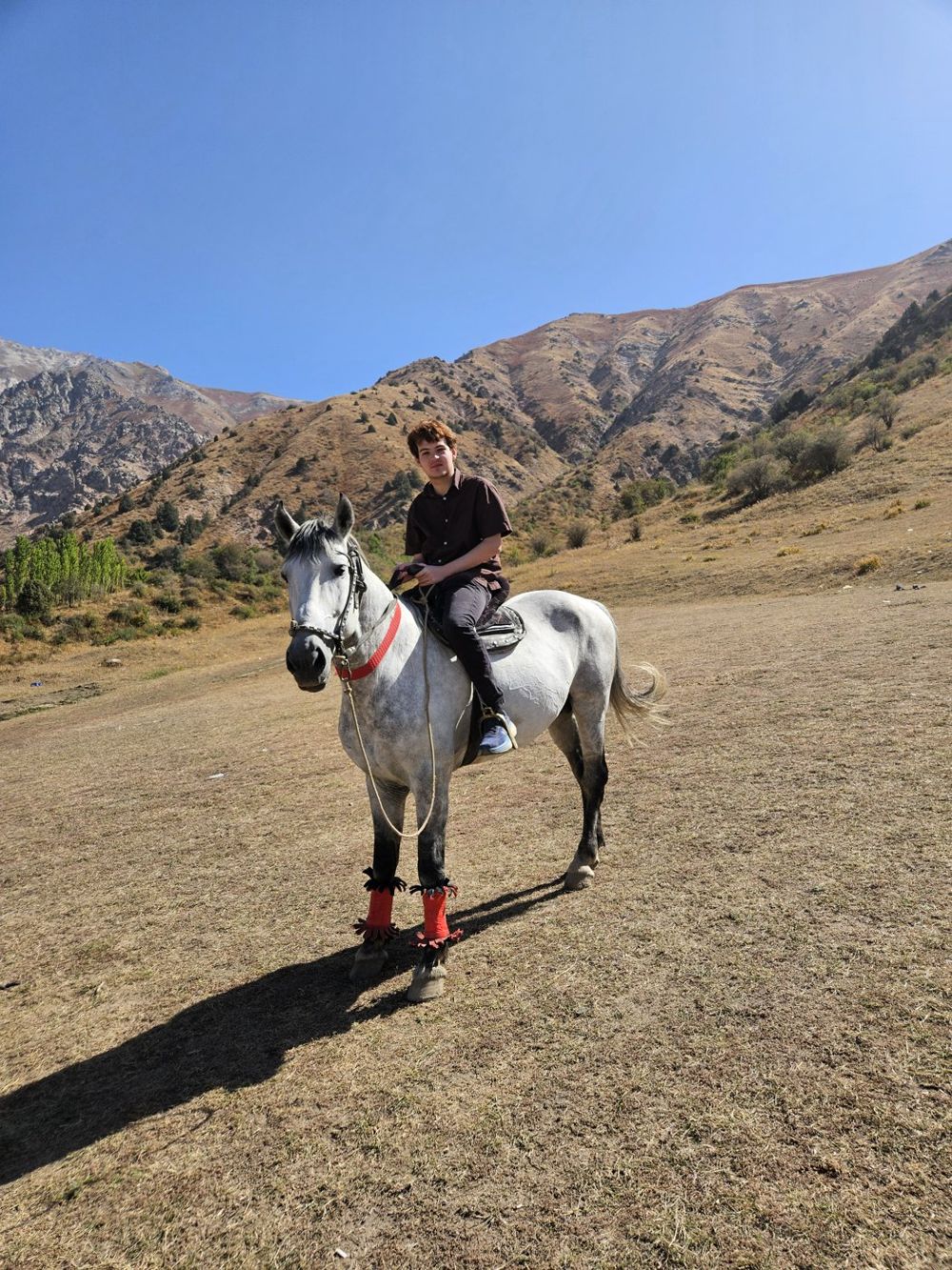 Cameron on a white horse in the mountains outside Tashkent